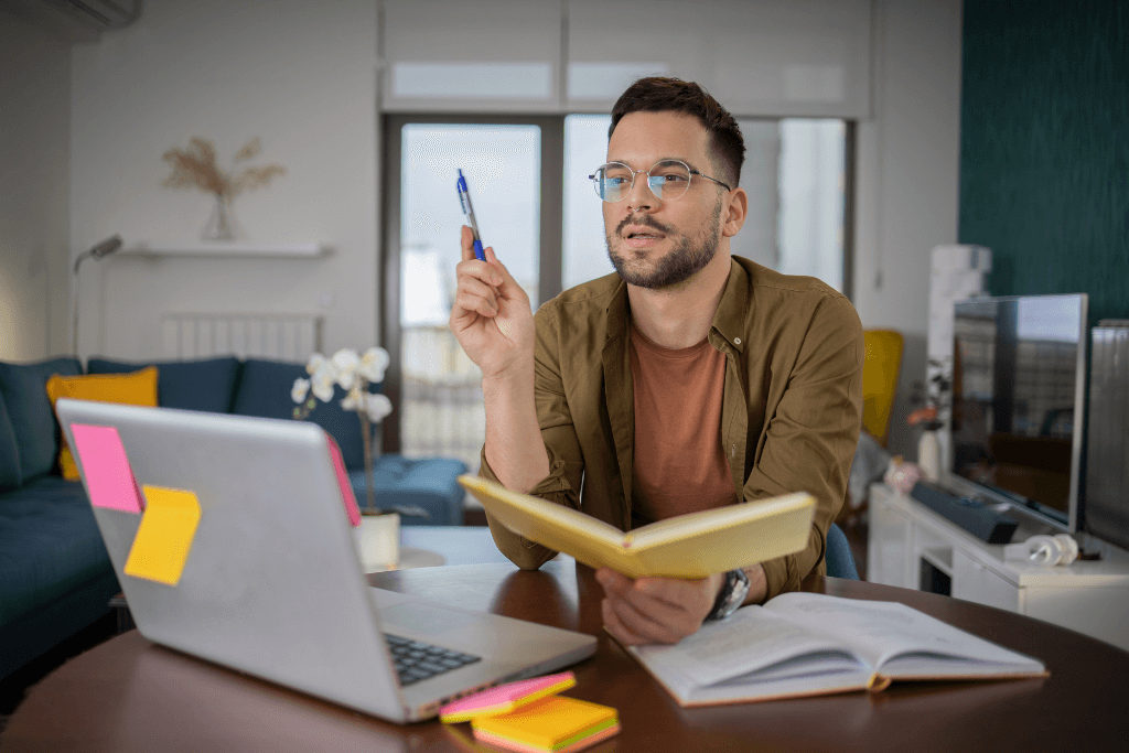a man engaged in self-learning sits at a table with a book in his hand